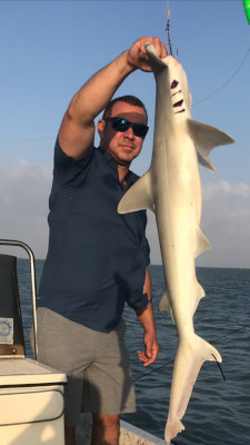 fisherman holding shark on fishing tour